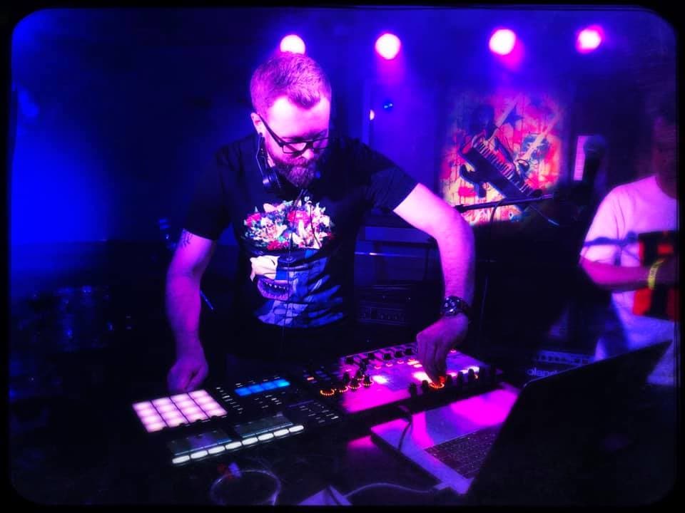 Taktile performing a live set on drum pads and controllers under blue and purple stage lights